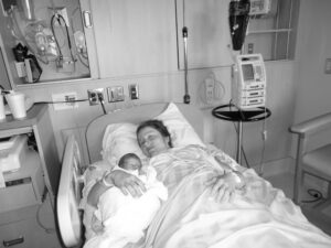 Veronique Rioux laying down in hospital bed with her newborn in her arms