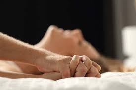 female lying down experiencing pleasure with hands holding