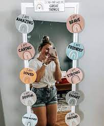 a women taking picture of herself in mirror surrounded with positive affirmations